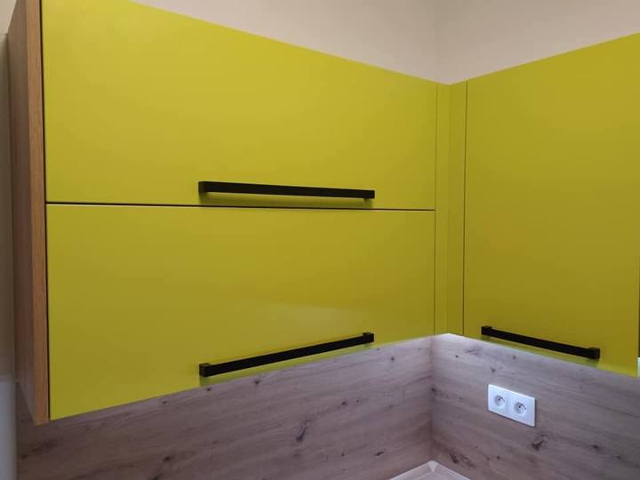 Limettengrüne Oberschränke mit schwarzen Griffen über Holzdekor