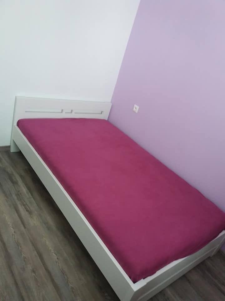 Weißes Kinderbett steht bei violetter Wand