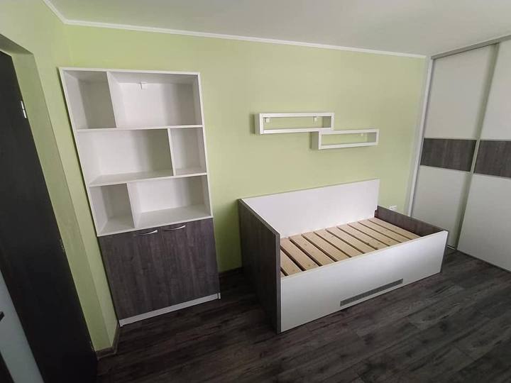 Weißes Bett und Regal mit Böden im Zimmer mit grüner Wand