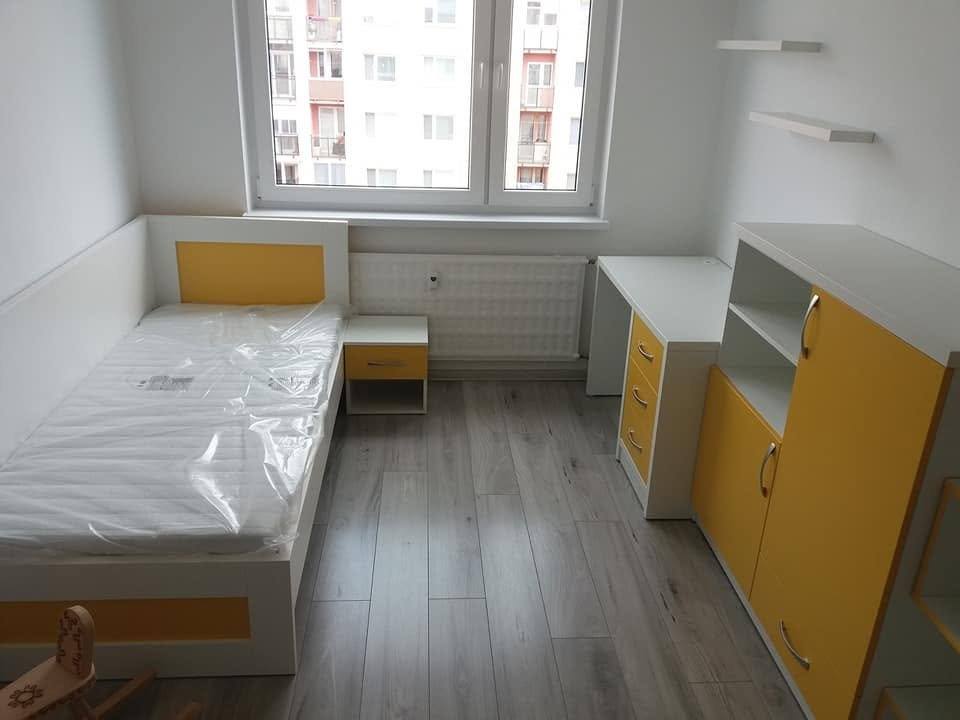 Bett mit orangefarbenem Nachtkästchen am Fenster mit Stadtblick