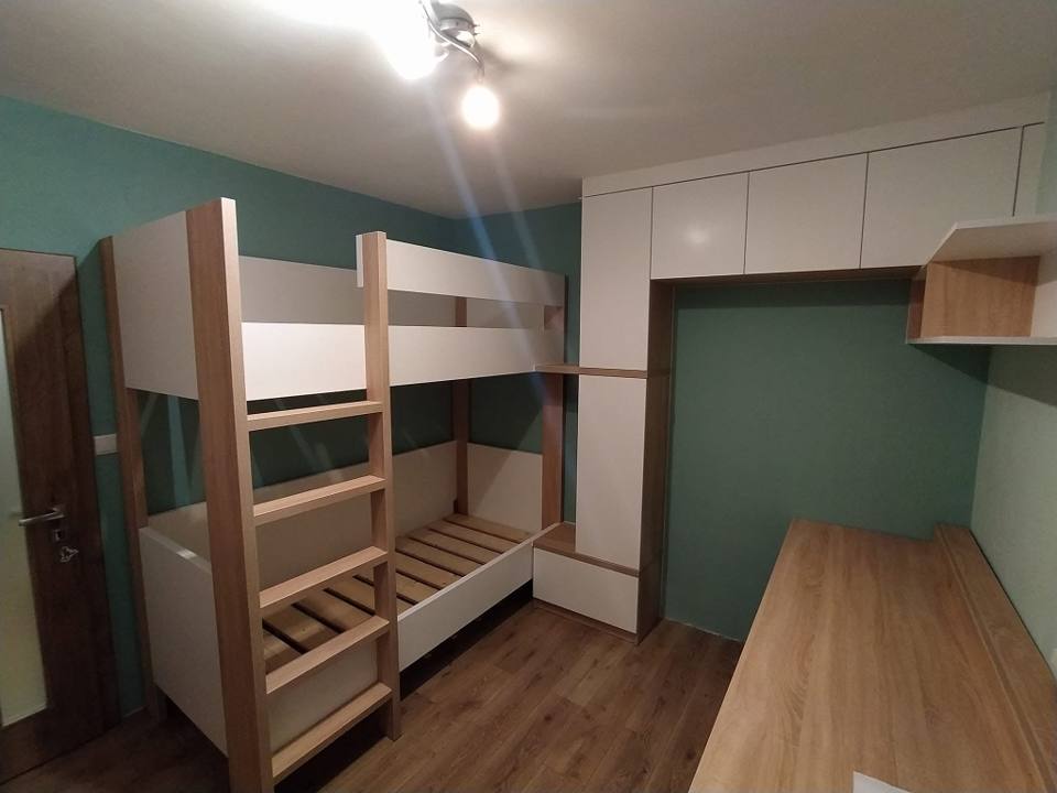 Kinderzimmer mit Etagenbett und weißen Oberschränken über dem Schreibtisch