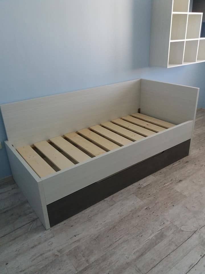Kinderbett mit anthrazitfarbenem Sockel vor blauer Wand