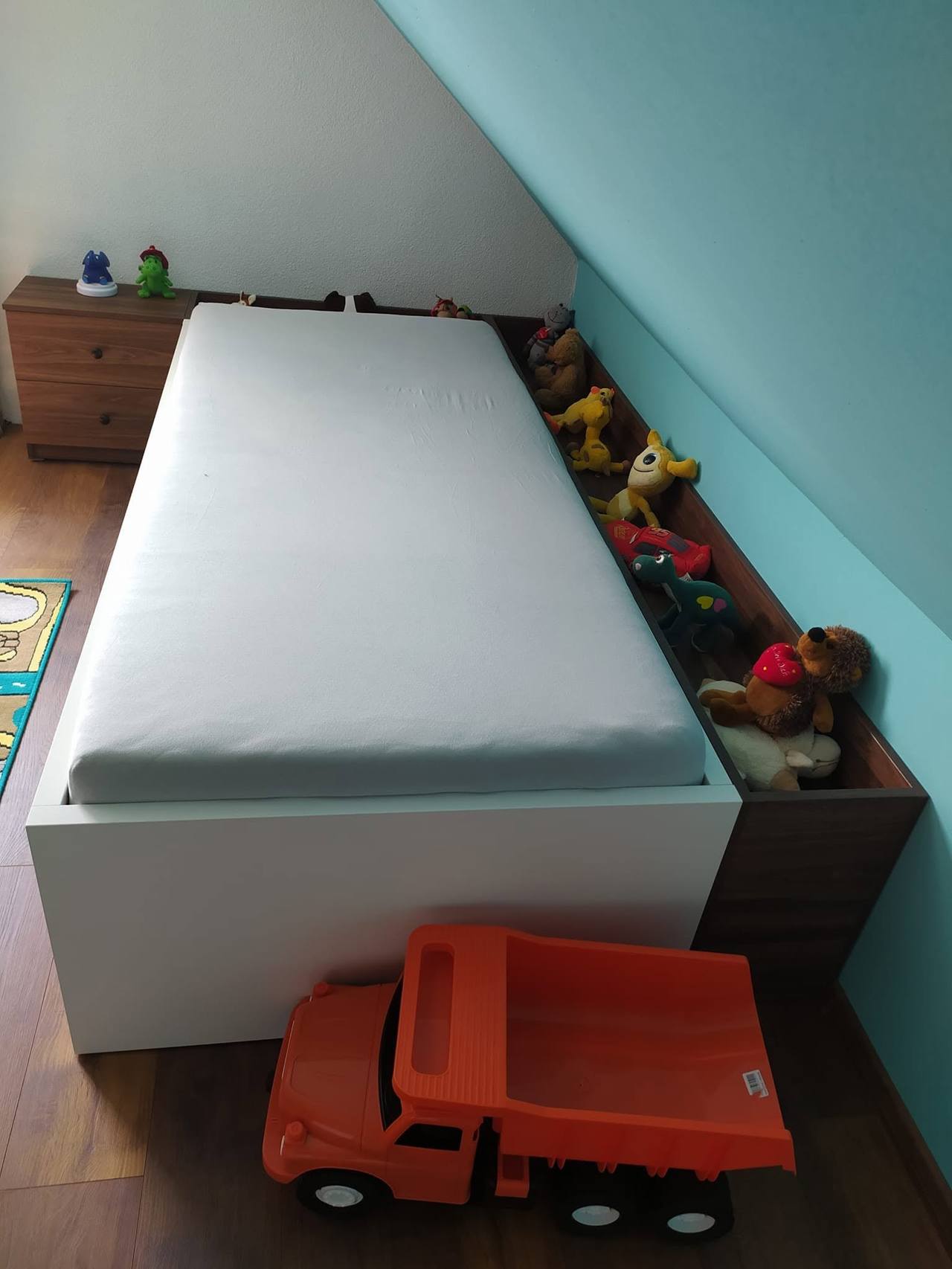 Posteľ pri šikmine s hračkou a plyšákom na matraci