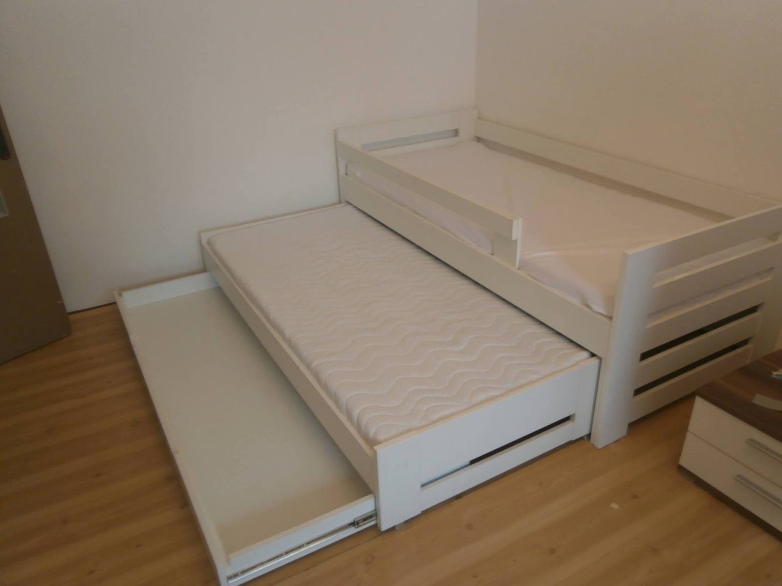 Vysunutá prístelka na kolieskach pod krémovou posteľou