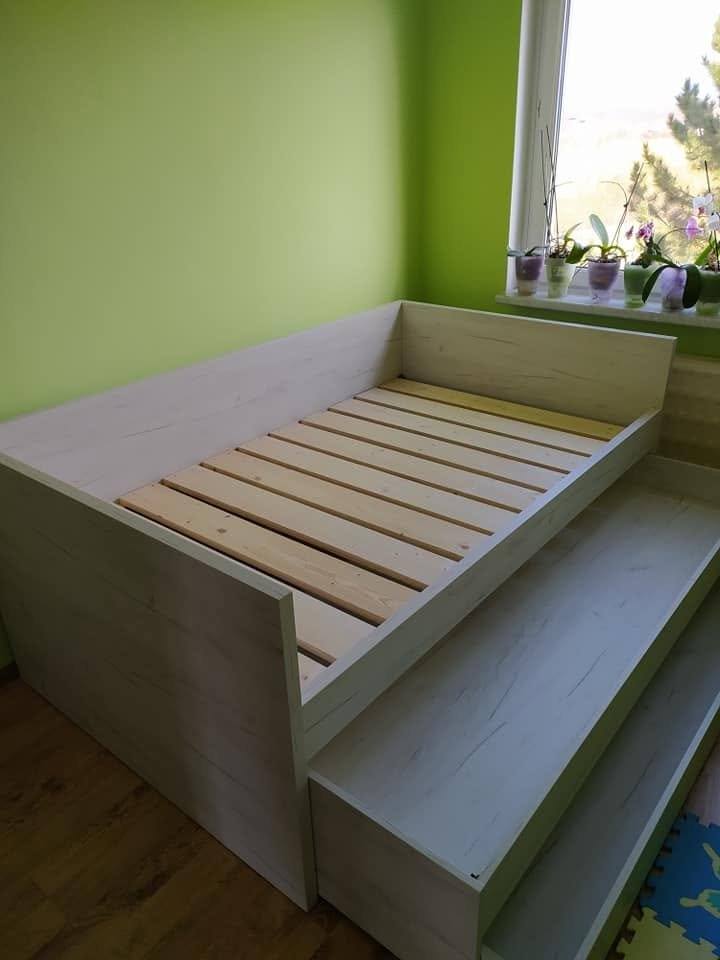 Bett in hellem Dekor mit ausgezogenem Zusatzbett unter dem Fenster