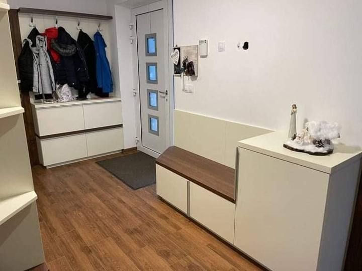Cremefarbene Sitzbank mit Nussauflage und Garderobe beim Eingang