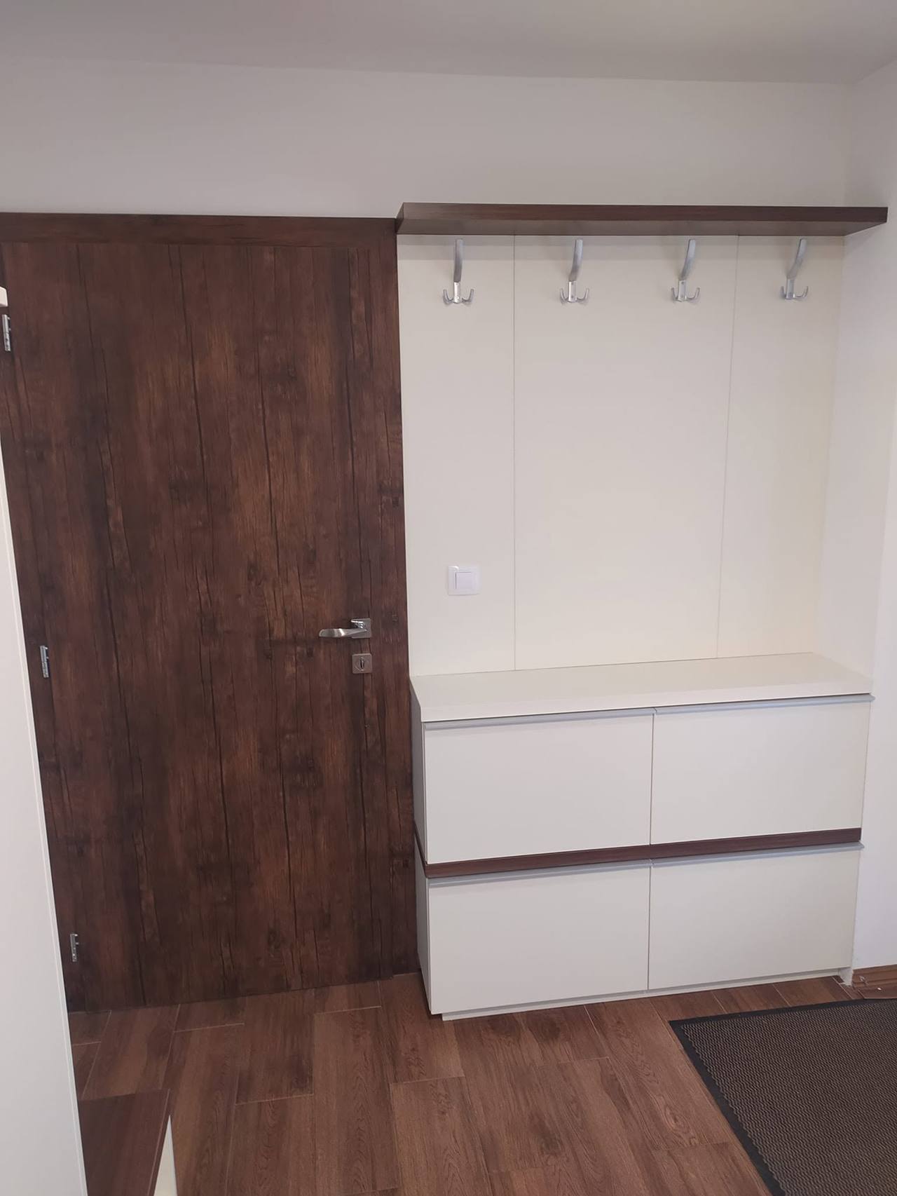 Garderobenpaneel mit Haken und weißen Laden neben der Tür