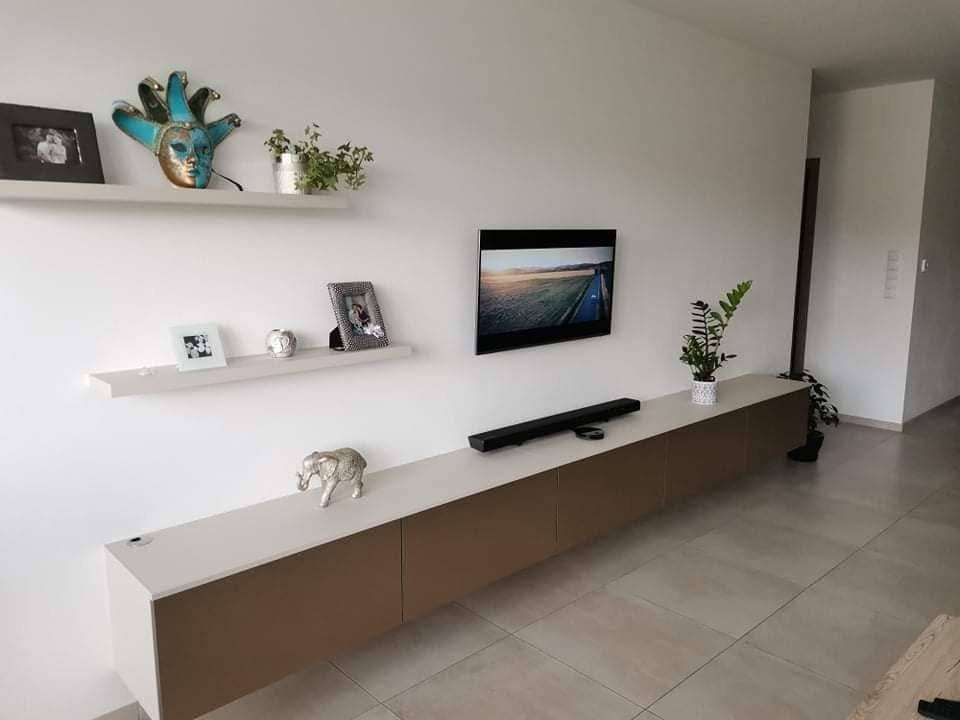 Hängeelement mit braunen Fronten und weißen Borden über dem Fernseher
