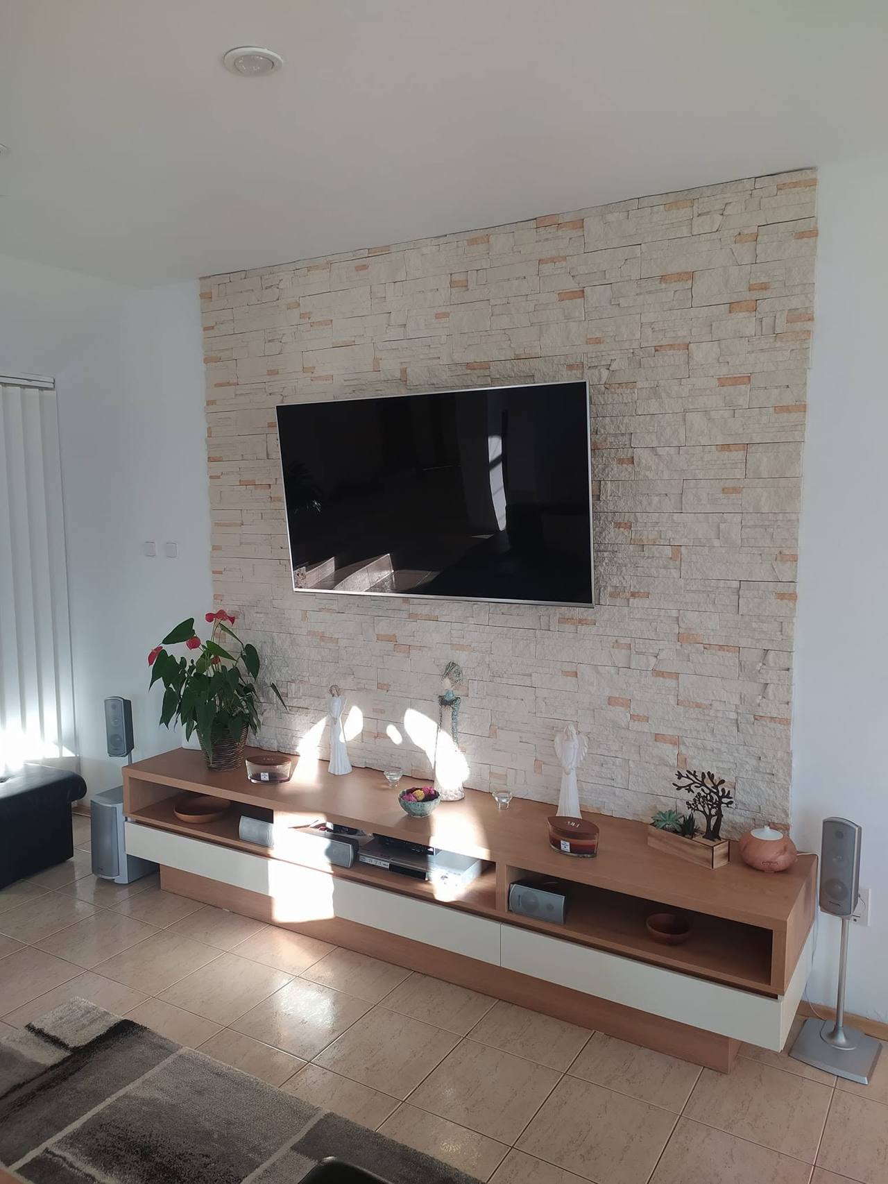 Lowboard unter dem Fernseher vor der Wand mit Steinverkleidung