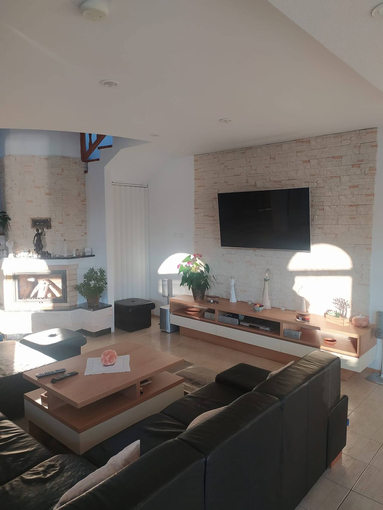 Wohnzimmer mit Lowboard vor der Steinwand und Sitzgruppe