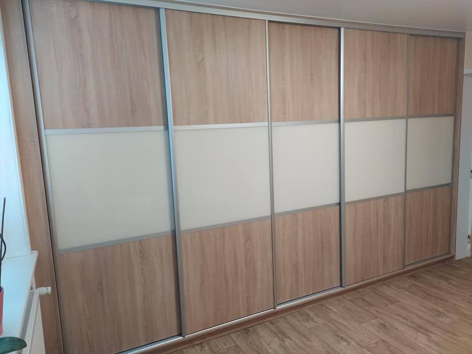 Schiebetürkasten über die ganze Wand in Eichendekor mit cremefarbenem Band.