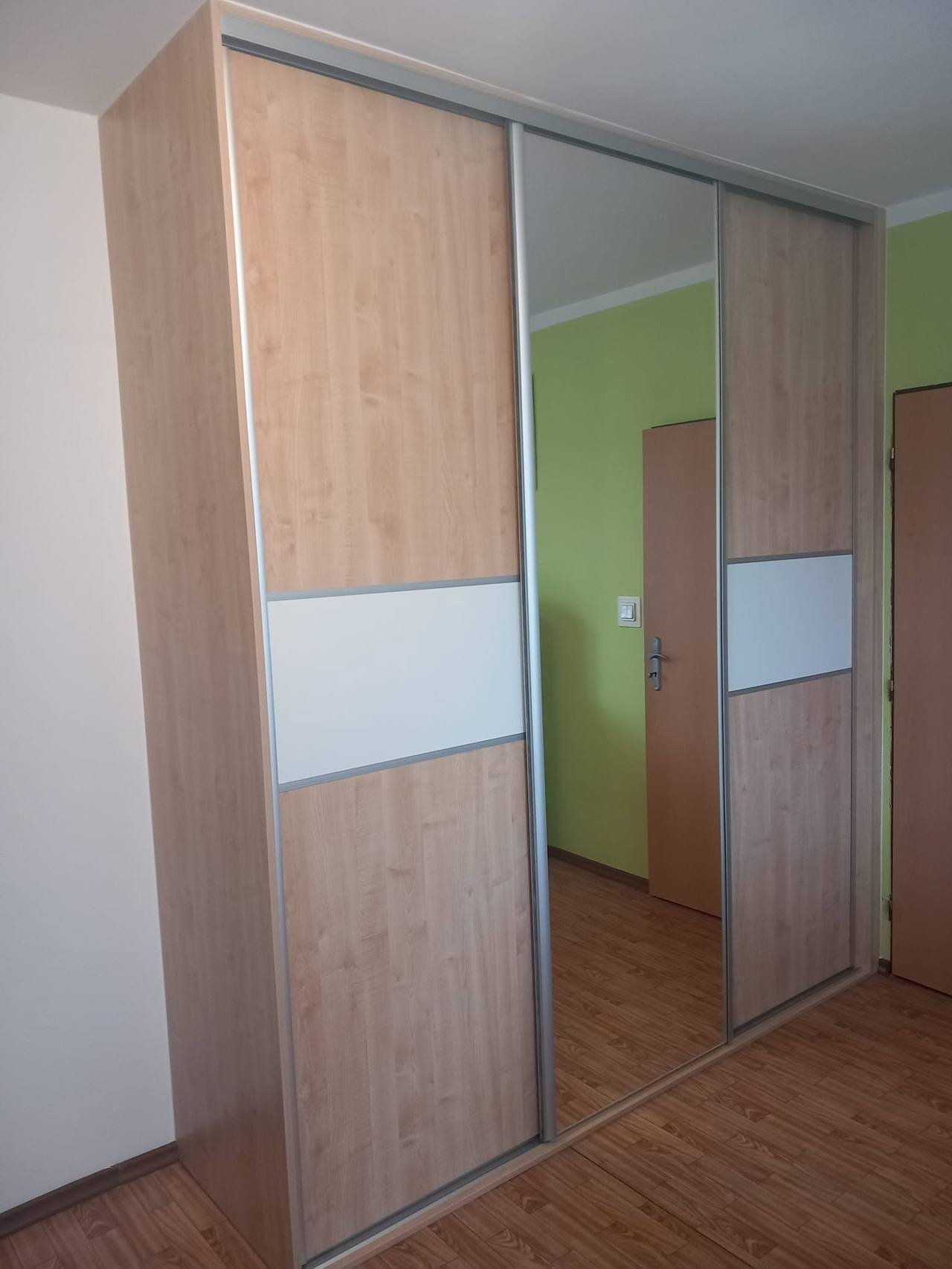 Eichenkasten mit weißem Streifen und Spiegel an grüner Wand