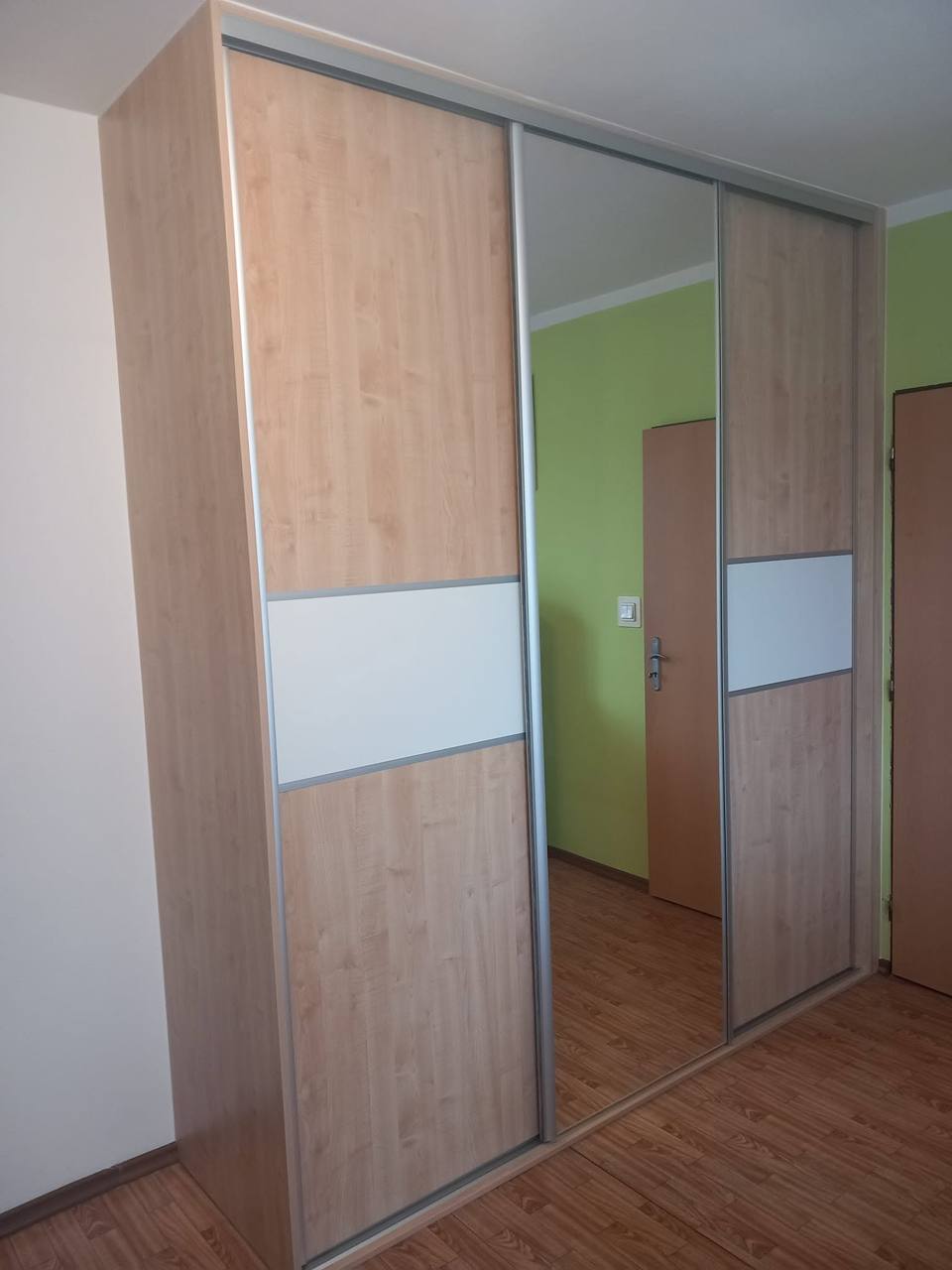 Eichenkasten mit weißem Streifen und Spiegel an grüner Wand