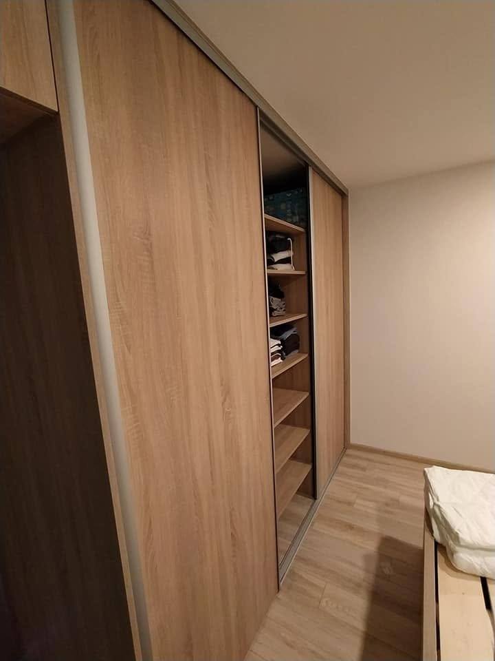 Schiebetürenkasten in Eiche-Dekor mit Fächern neben dem Bett