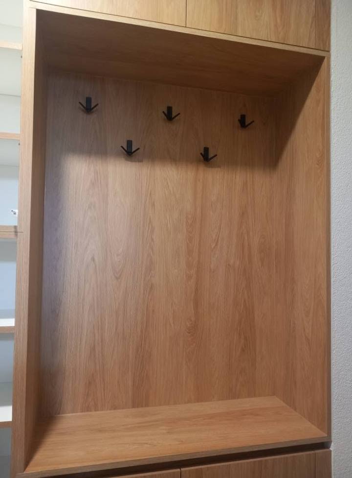 Detail der Nische mit schwarzen Haken in zwei Reihen und Bank