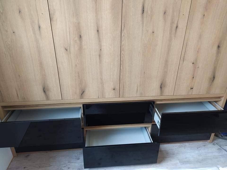 Eichenkasten mit ausgezogenen schwarzen Hochglanz-Laden im unteren Bereich.