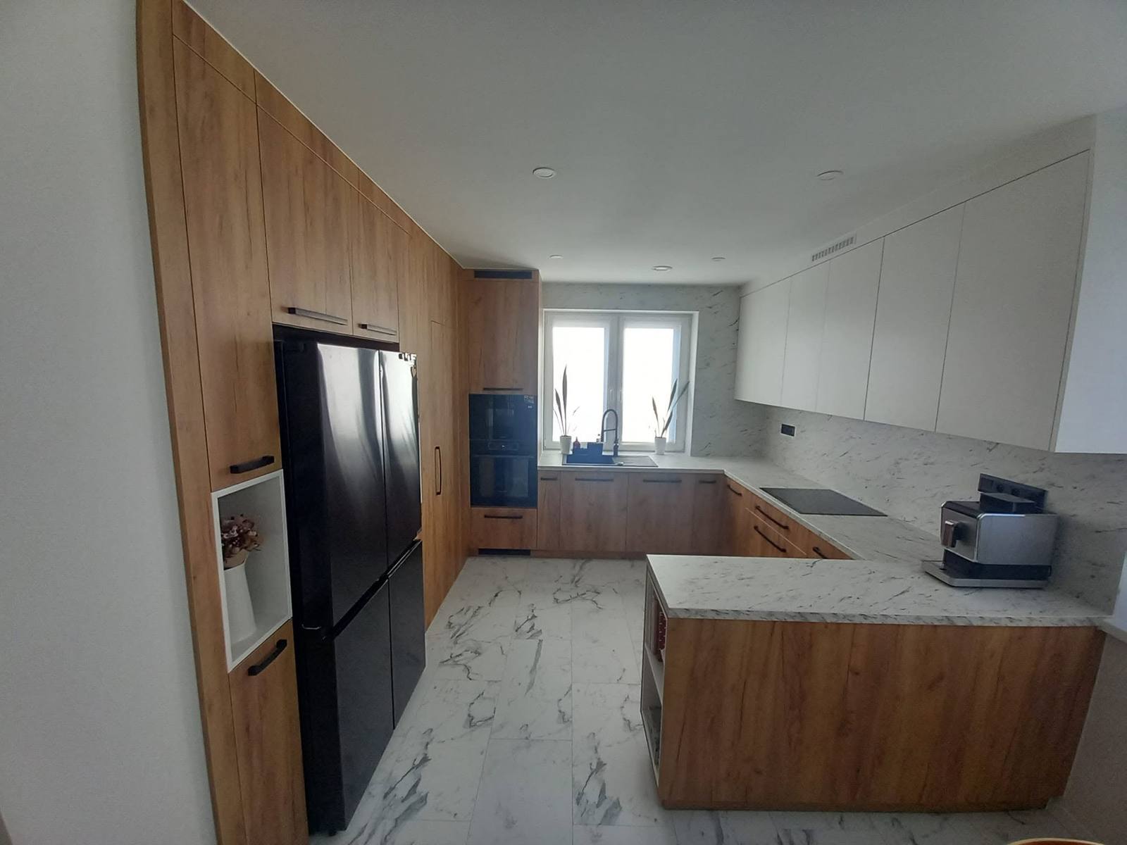 Eichenküche mit Insel, Kastenwand und schwarzem Kühlschrank