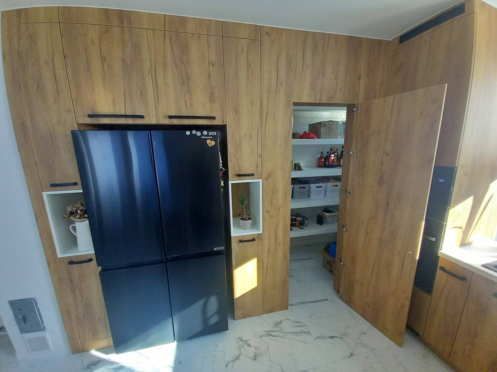Geöffnete Speistür in der Eichenwand neben dem Kühlschrank