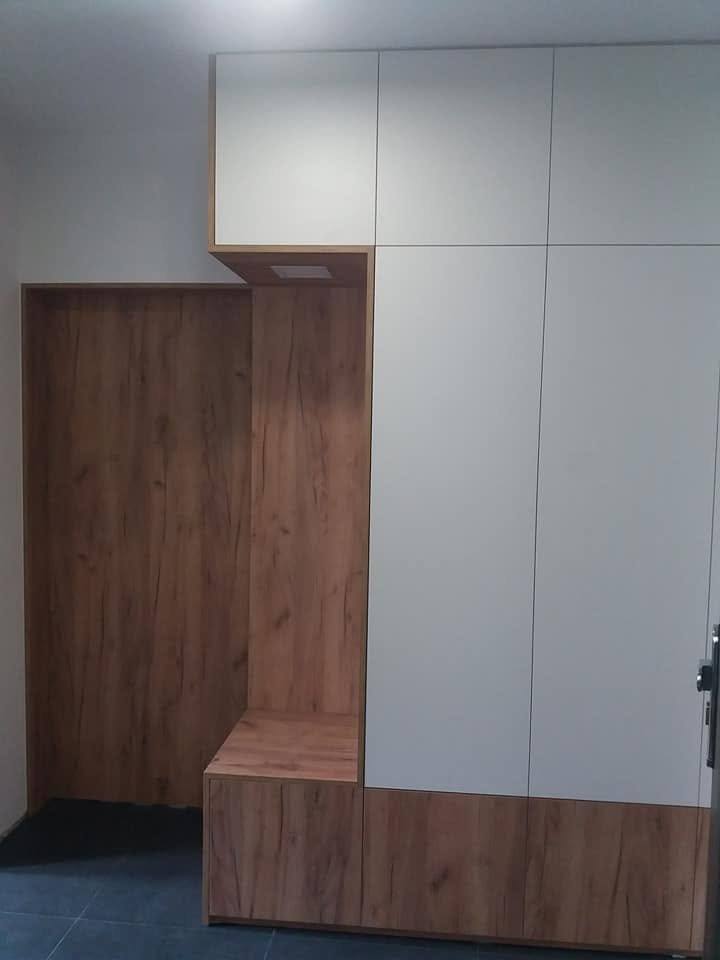 Weißer griffloser Kasten neben der Eichennische mit Sitzbank