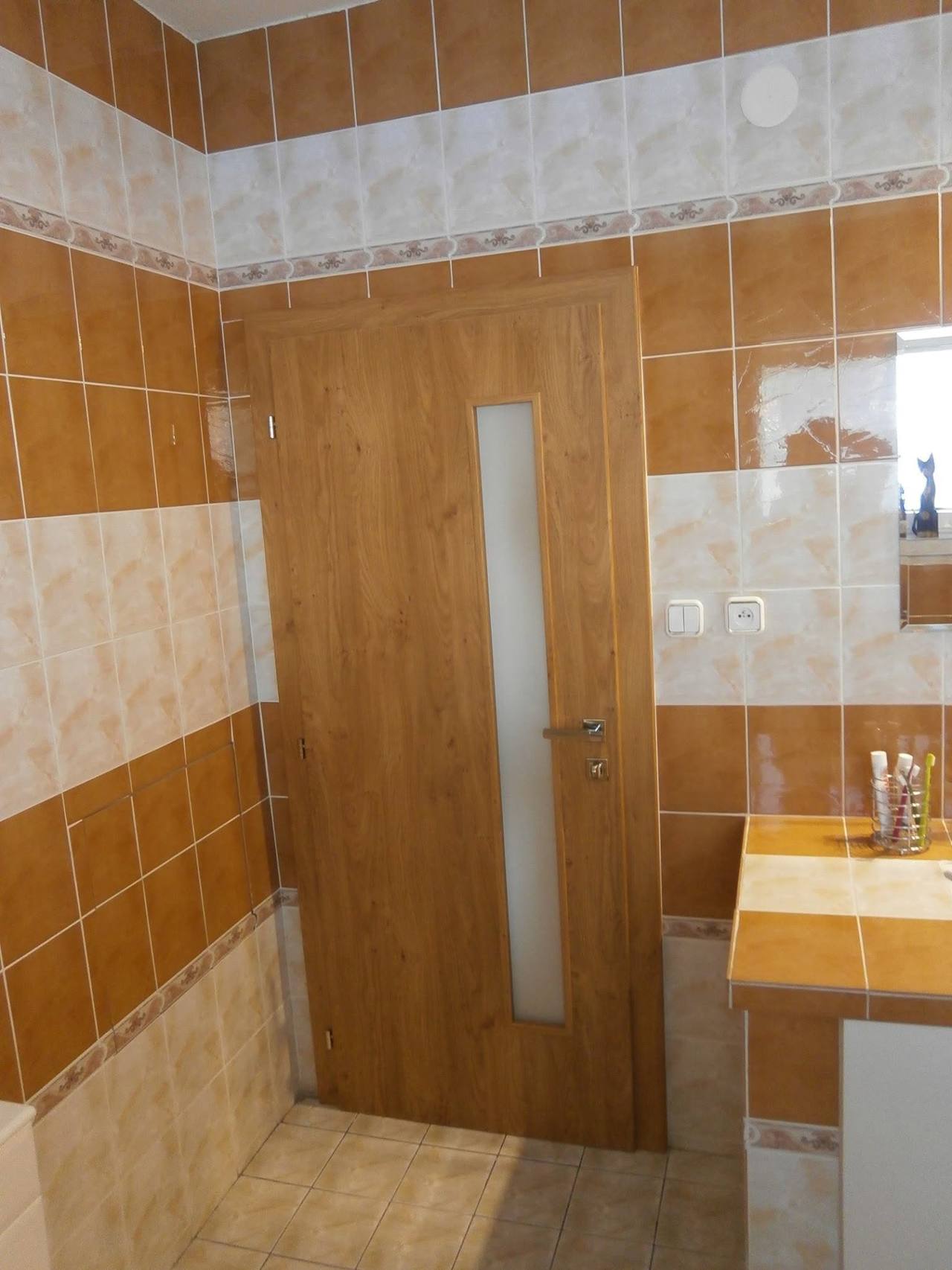 Eichentür und Retro-Wandfliesen aus anderem Blickwinkel beim Waschbecken