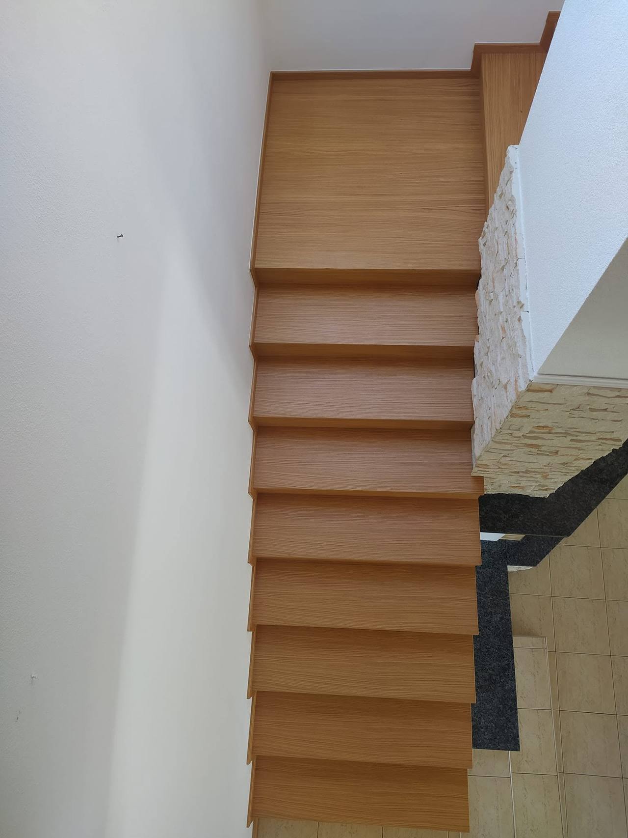 Rovné schodisko obložené dubom pri kamennom obklade zhora