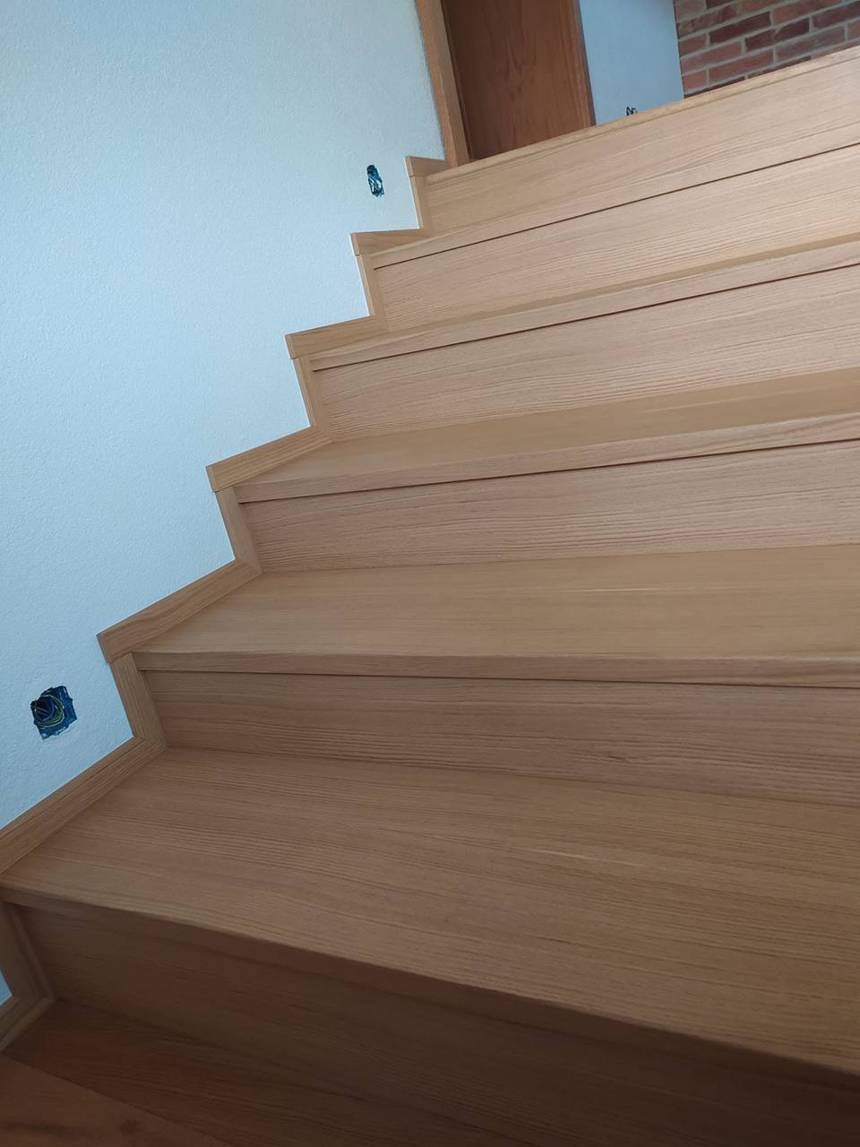 Eichenstiege von unten zwischen glatten weißen Wänden gesehen