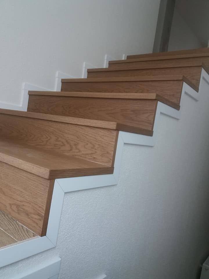 Geölte Eichenstiege entlang der weißen Wand aus seitlicher Sicht