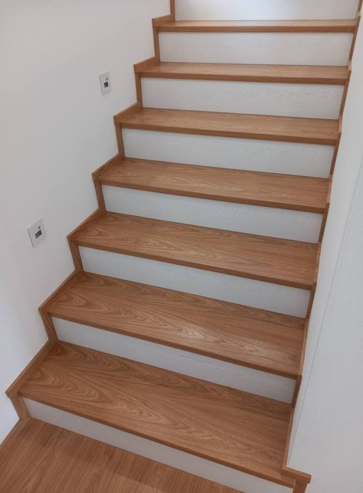 Eichenstiege mit weißen Setzstufen und Wandspots von unten gesehen