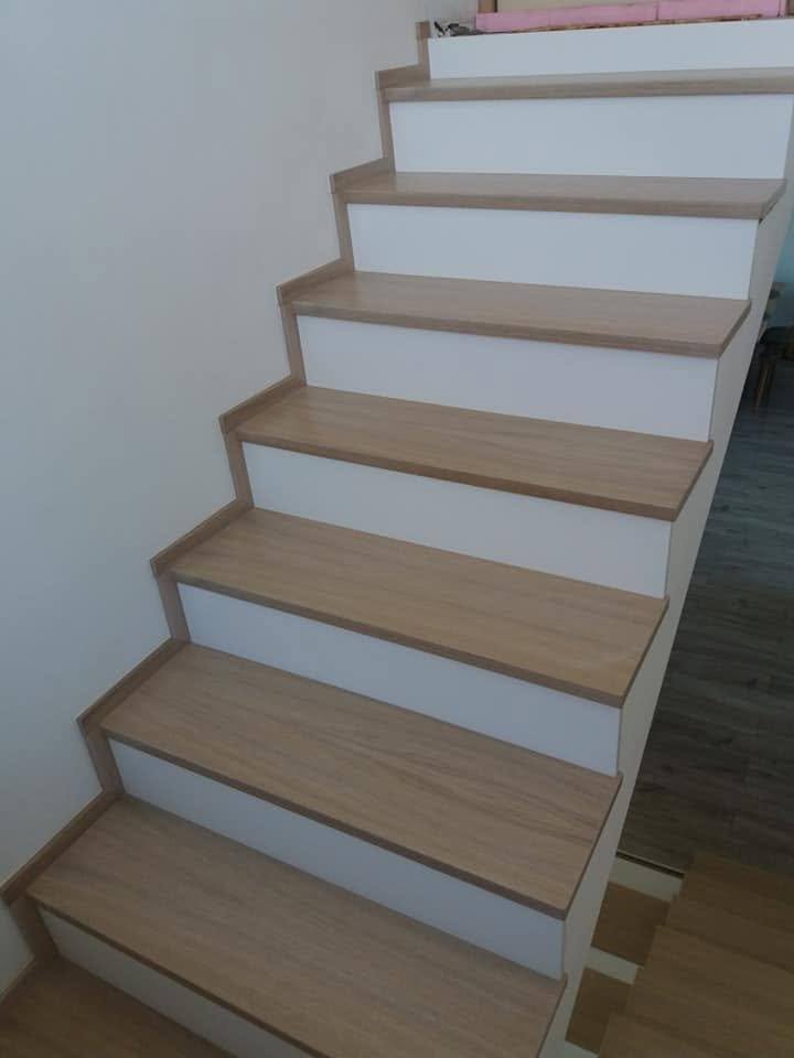 Eichenstiege mit weißen Setzstufen entlang der glatten weißen Wand