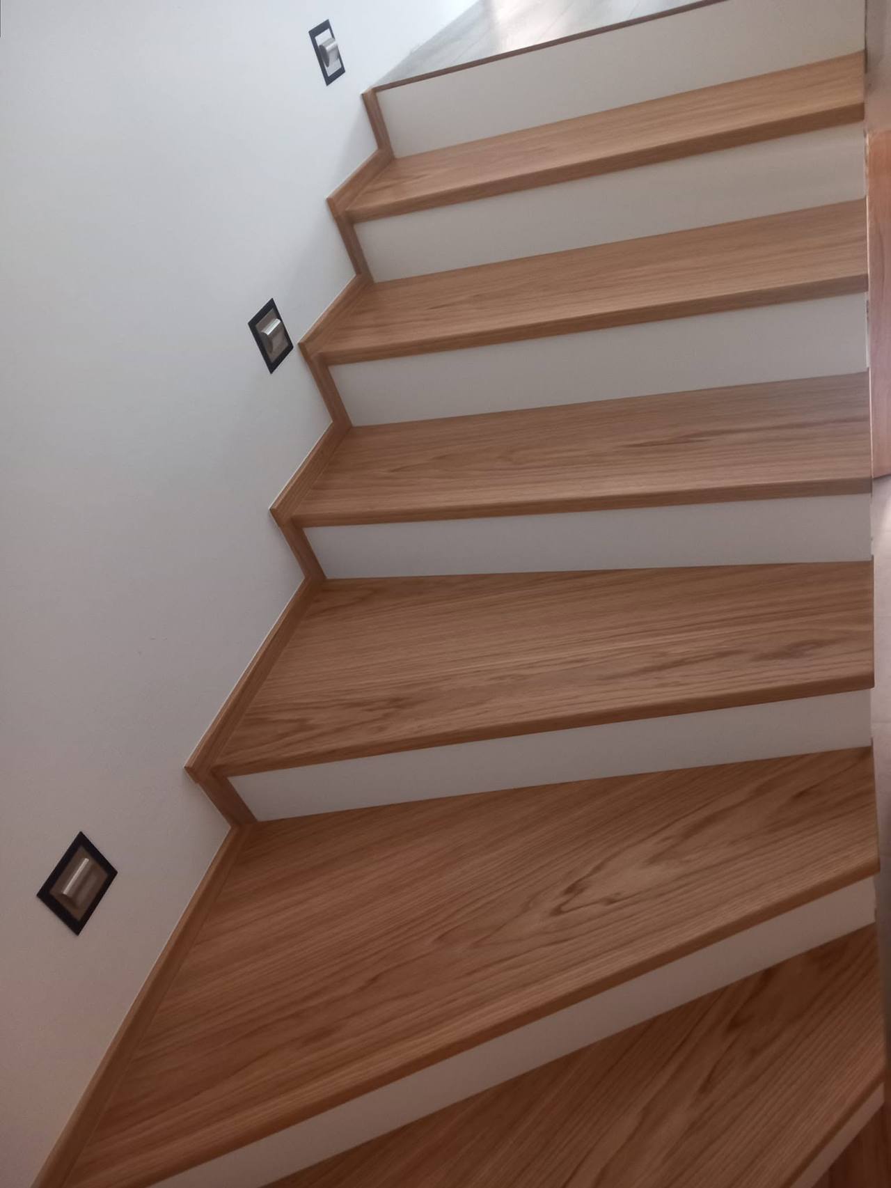 Eichenstiege mit weißen Setzstufen und Wandspots