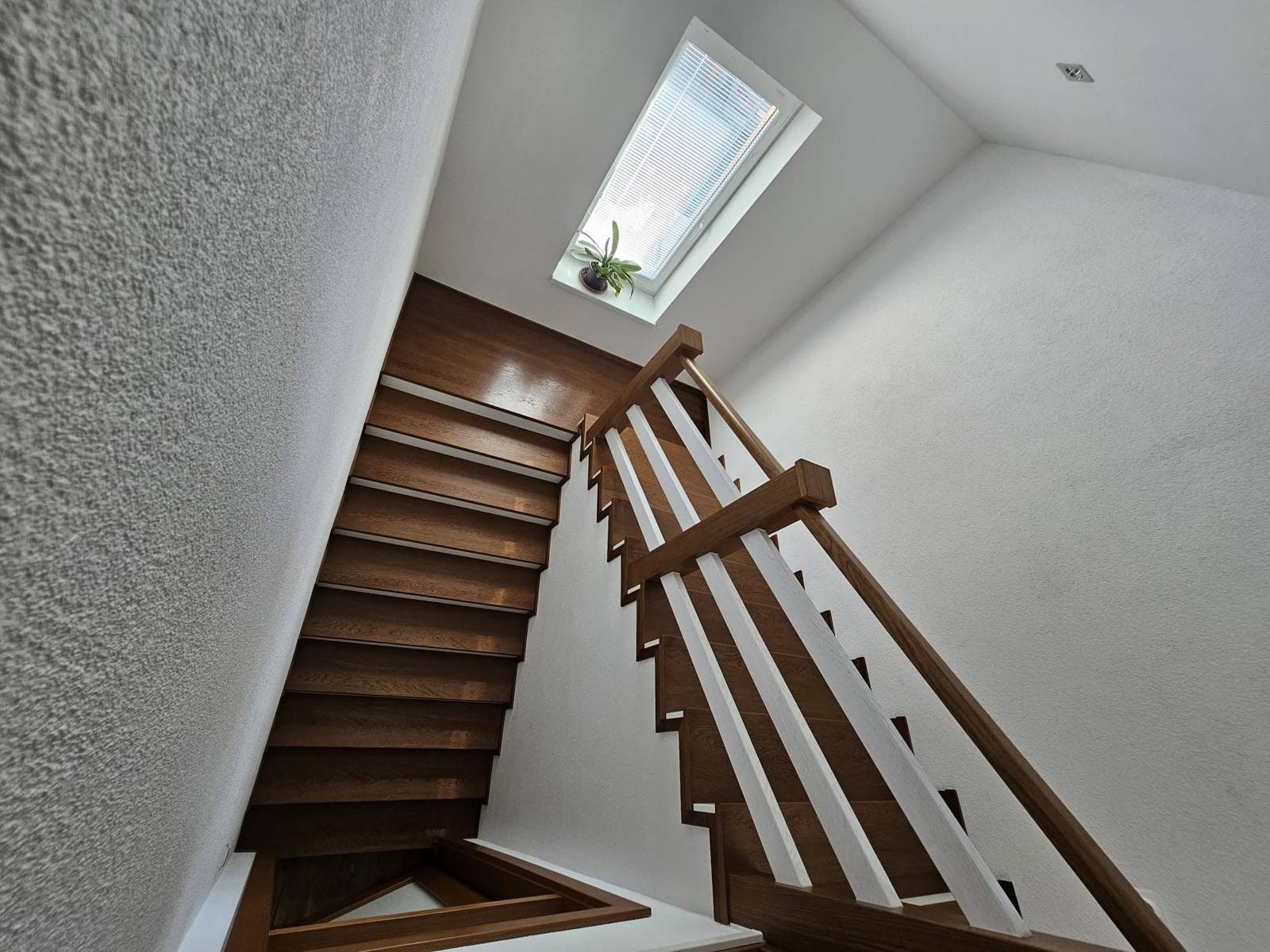 Eichenstiege mit Geländer unter dem quadratischen Dachfenster im Dachgeschoß