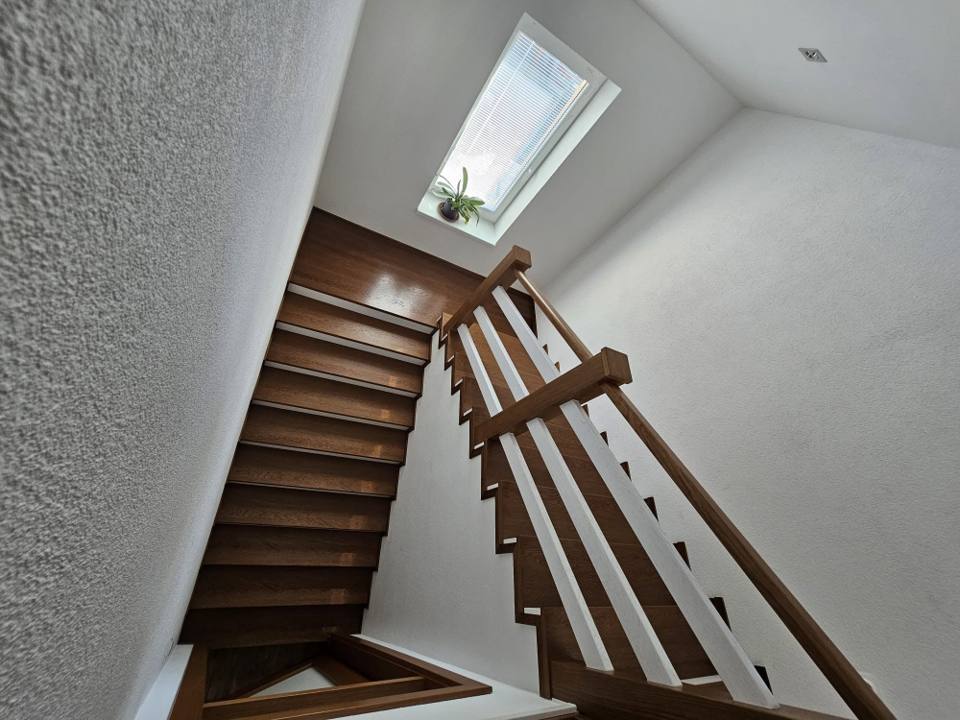 Eichenstiege mit Geländer unter dem quadratischen Dachfenster im Dachgeschoß