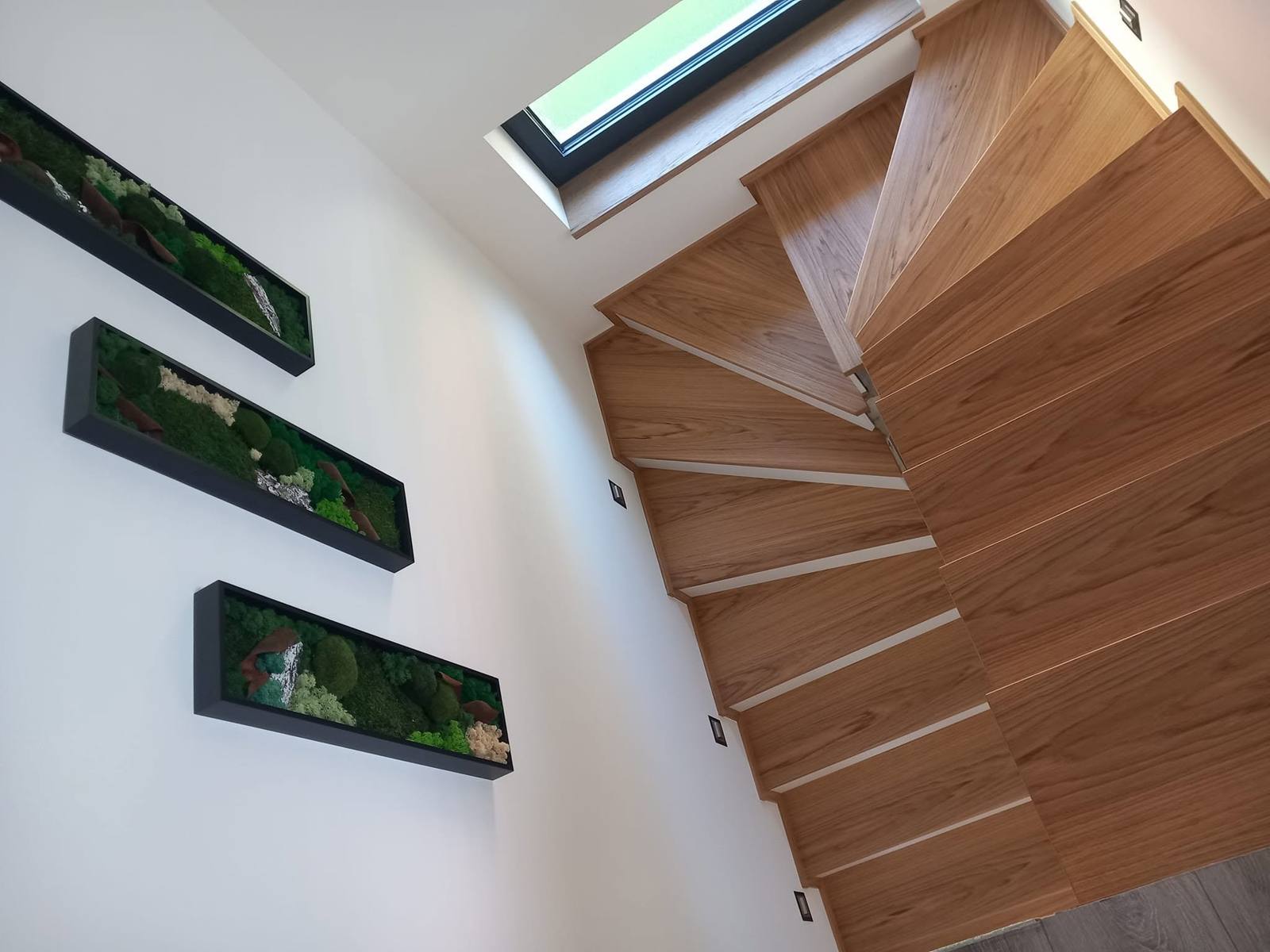 Gewendelte Eichenstiege mit drei gerahmten Bildern an der Wand