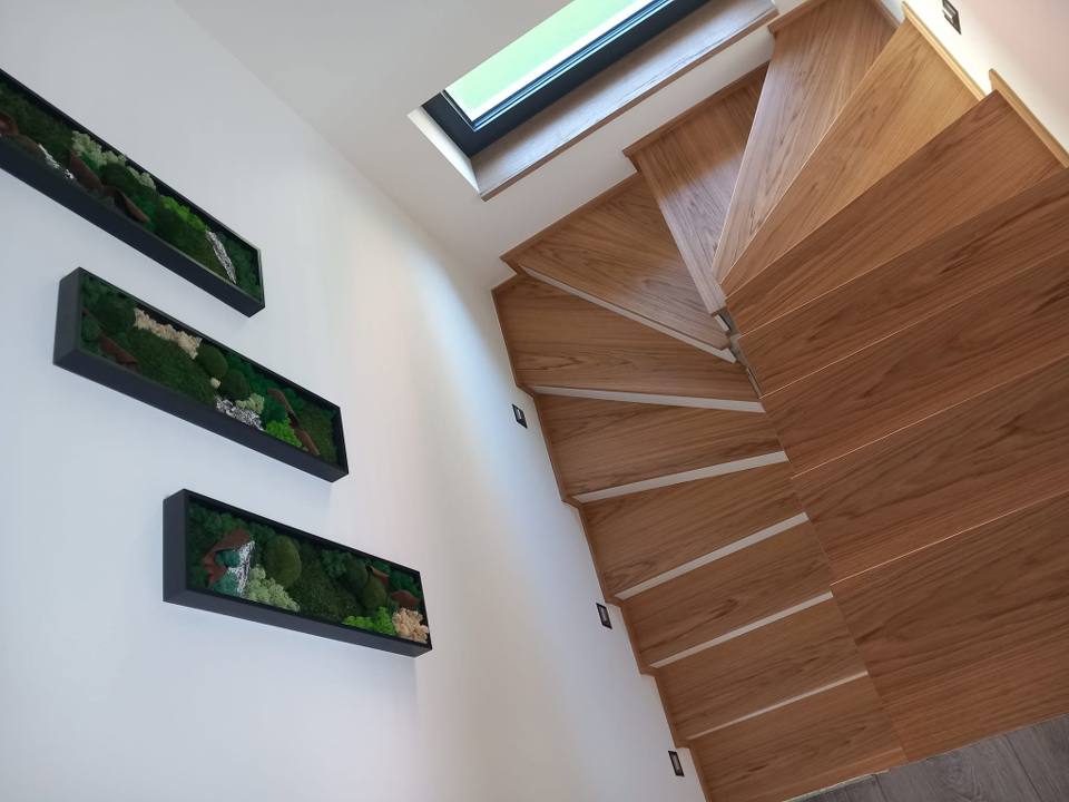 Gewendelte Eichenstiege mit drei gerahmten Bildern an der Wand