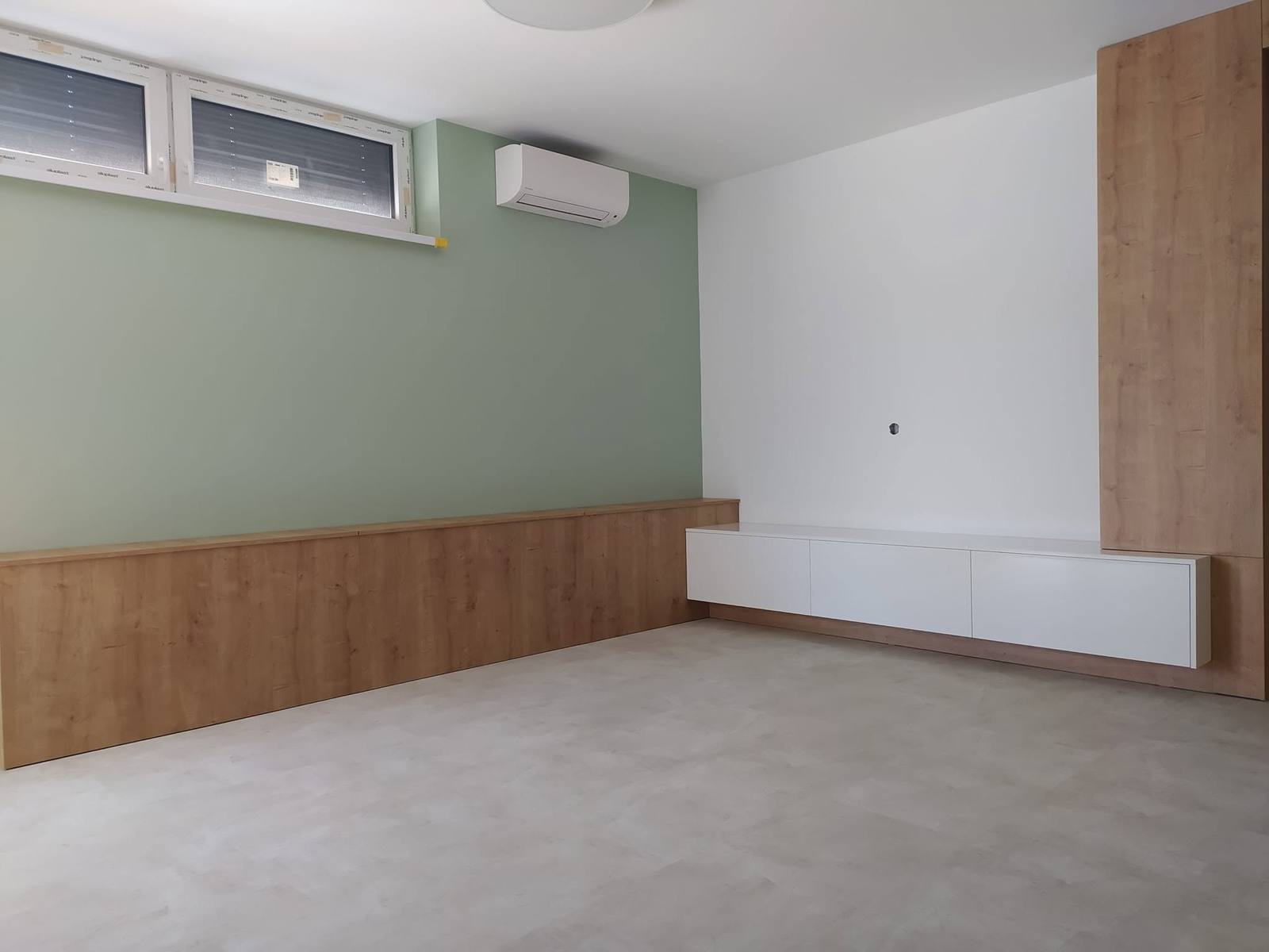 Niedrige Box in Eichendekor an grüner Wand und weiße Hängekästen