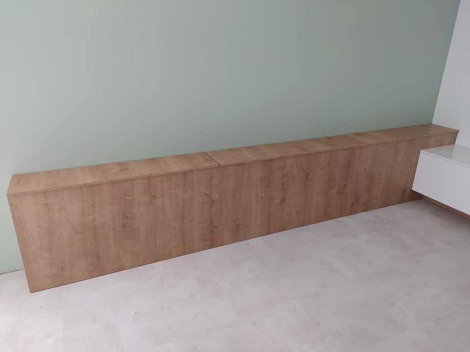 Lange niedrige Box in Eichendekor an der grünen Schlafzimmerwand