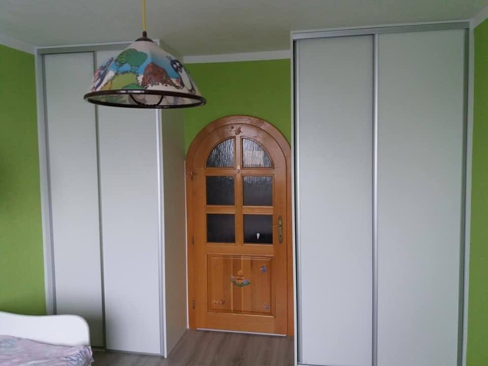 Dve biele skrine po stranách drevených dverí s oblúkom