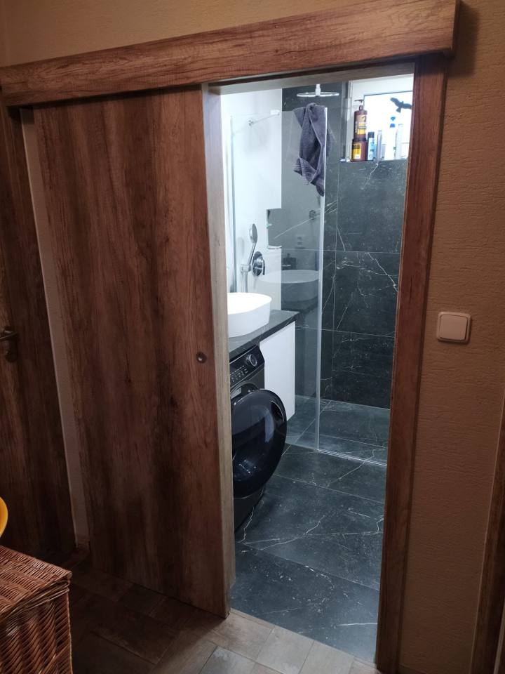 Offene Schiebetür im Nussbaumdekor zum Badezimmer
