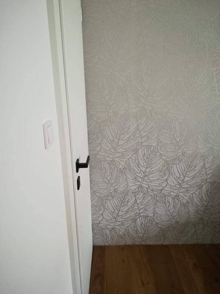 Offene weiße Zimmertür bei tapezierter Wand