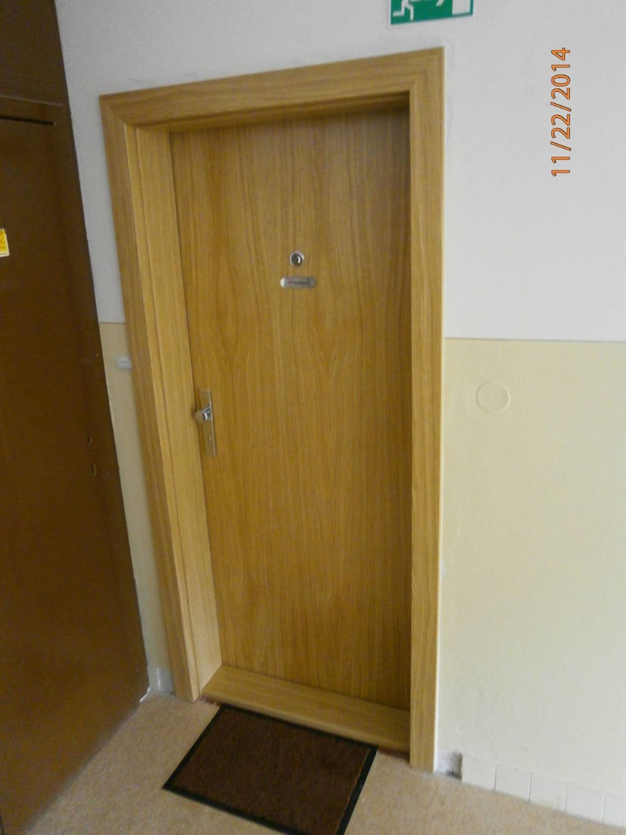 Dubové dvere v spoločnej chodbe s rohožou pred prahom