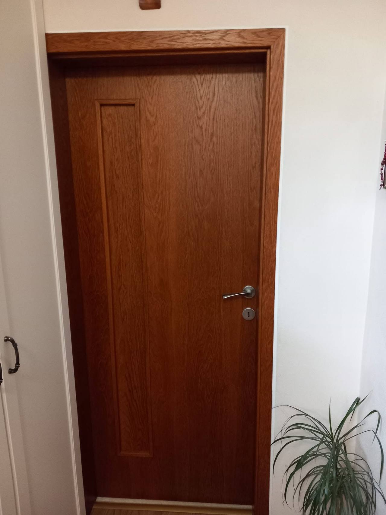 Tür in dunklem Kirschdekor mit feiner vertikaler Rille beim Fenster.