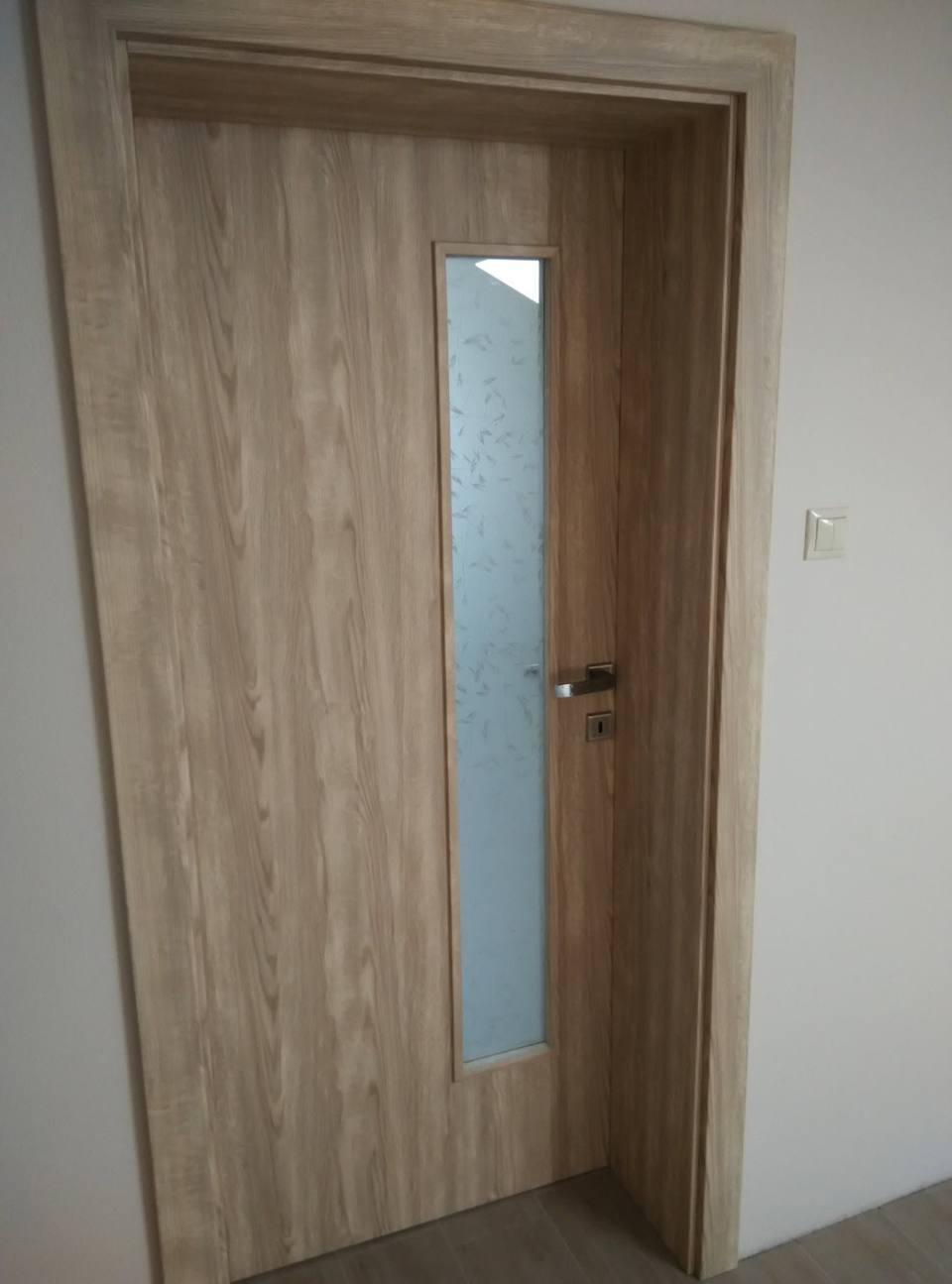 Tür in Eichendekor mit schmalem seitlichem Milchglasstreifen beim Fenster.