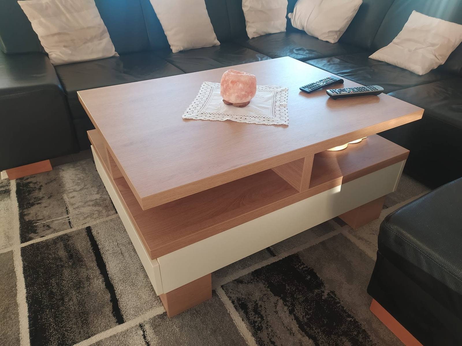 Zweifarbiger Couchtisch vor dem schwarzen Ledersofa