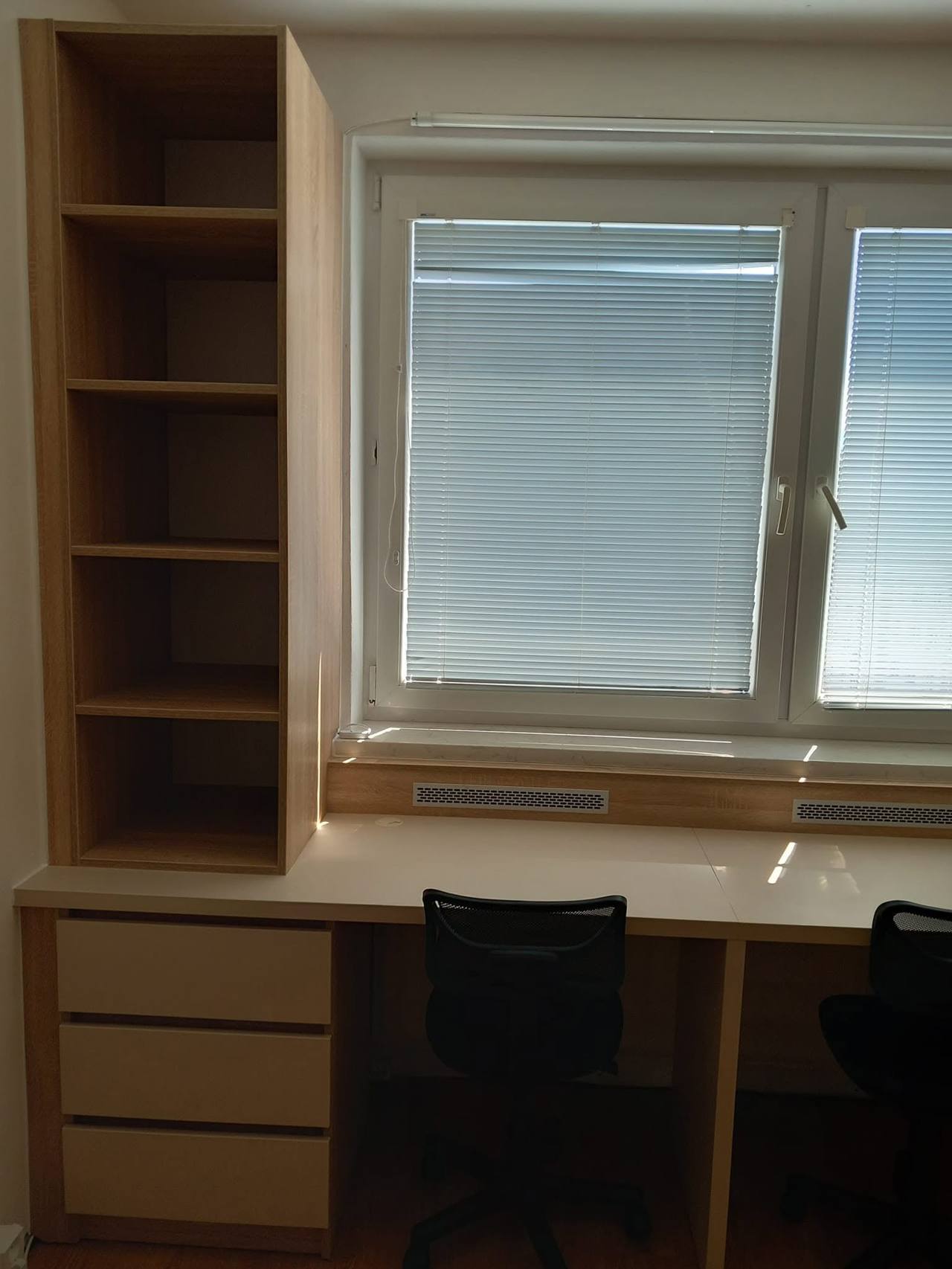 Schreibtisch am Fenster, beidseitig von hohen Eichenregalen begleitet