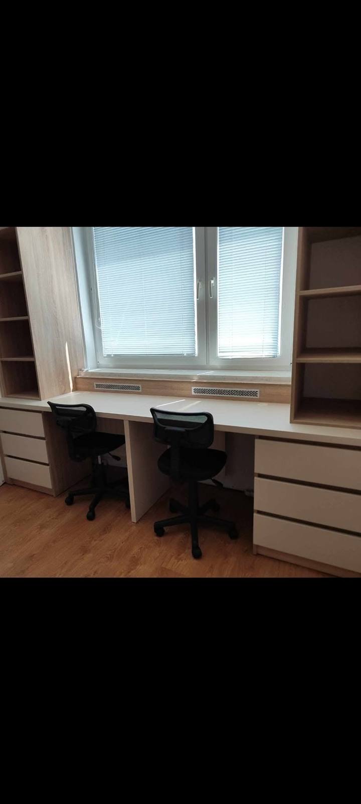 Blick auf den langen gemeinsamen Schreibtisch für zwei Kinder am Fenster