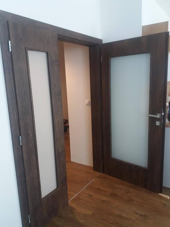 Halb geöffnete zweiflügelige Eichentür mit Milchglas auf Holzboden