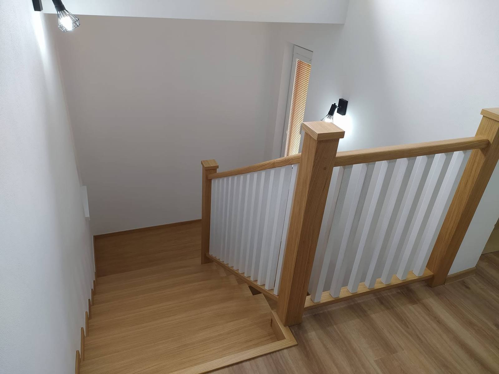 Galerie mit weißem Geländer und massivem Eichenhandlauf über der Stiegenöffnung