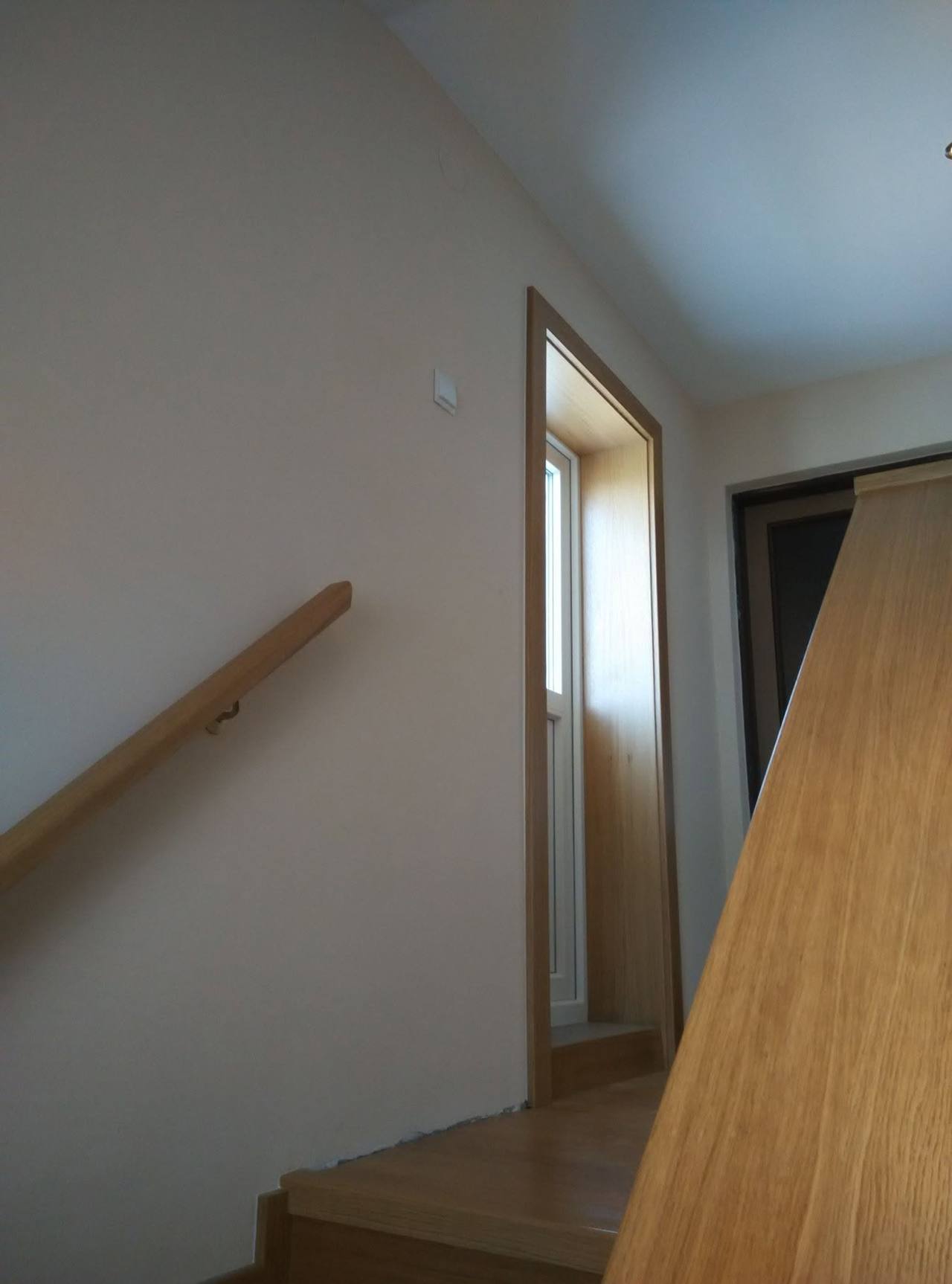 Oberer Austritt der Eichenstiege mit Holzhandlauf an der Wand