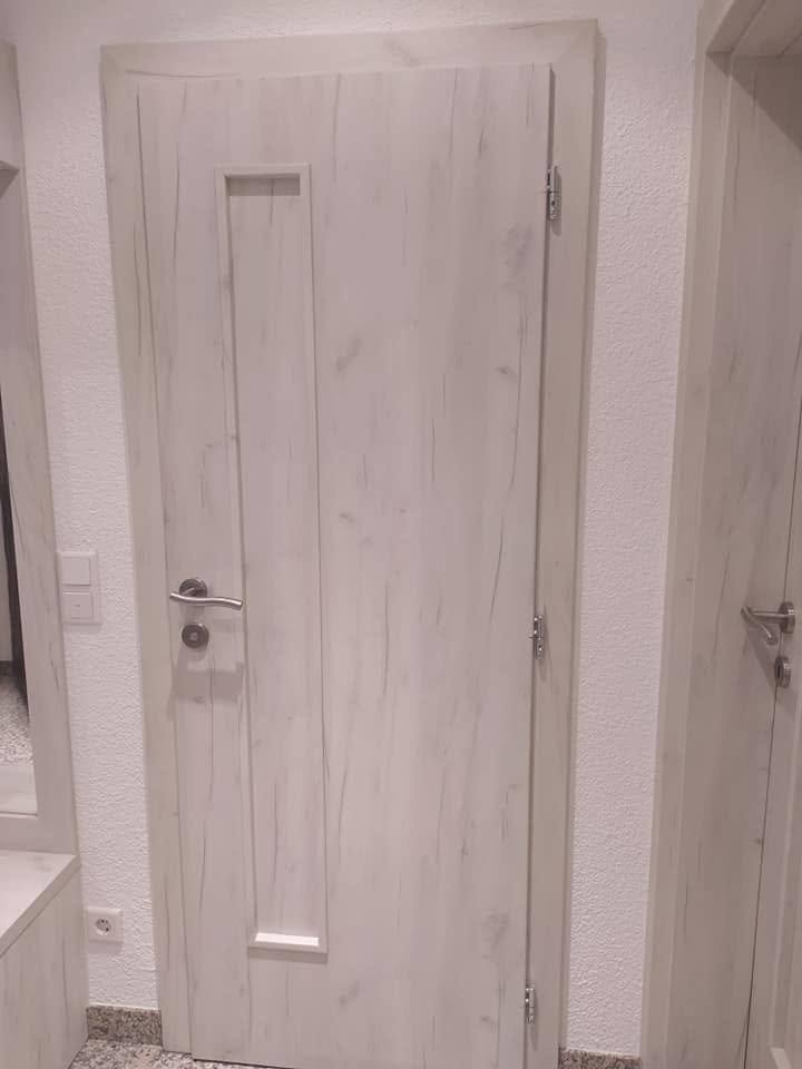 Innentür in gebleichter Eiche mit vertikaler Rille und langem Griff.