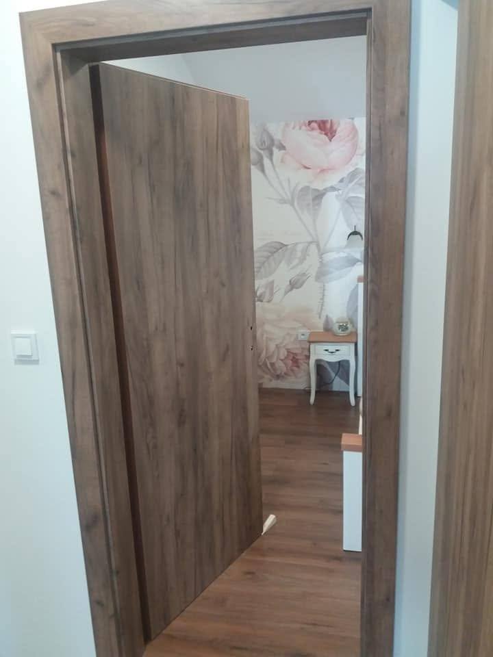 Otvorené dvere v dekore dub vedúce do izby s kvetinovou tapetou.